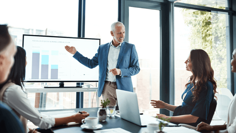 Man giving a presentation to colleagues showing positive business trends 