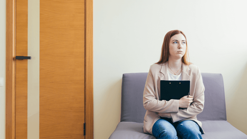 Woman sits in a hall and looks concerned