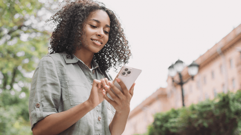 Young professional woman looking at her phone outside