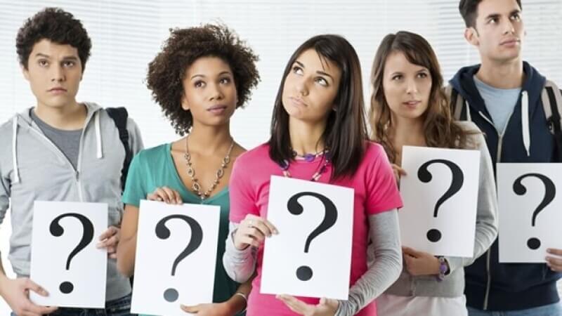College-aged people holding question marks 