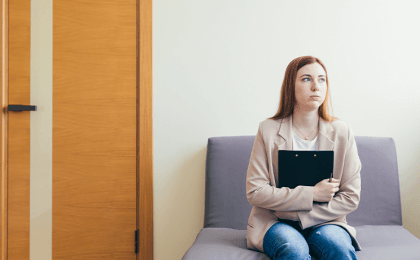 Woman sits in a hall and looks concerned