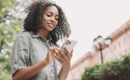 Young professional woman looking at her phone outside