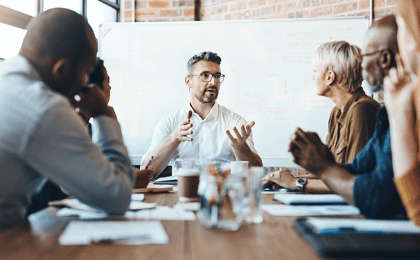 Manager sits at head of table talking to his coworkers