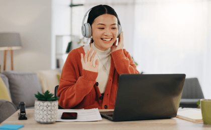 Young woman waving at computer screen in home office