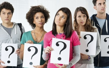College-aged people holding question marks 