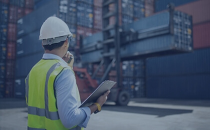 man with hard hat in front of shipping containers